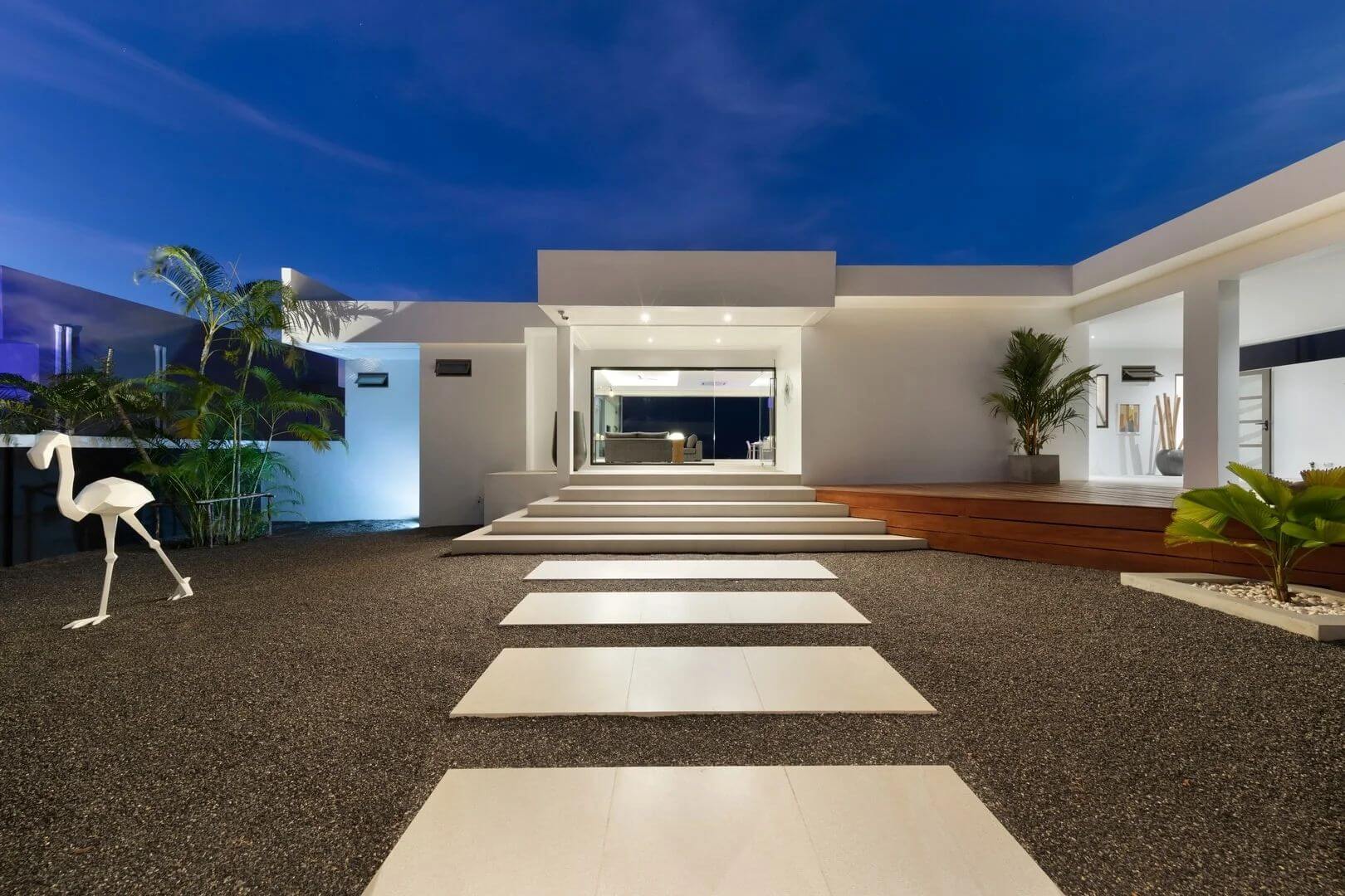 The entrance court at night — stepping stones to the lit living pavilion.