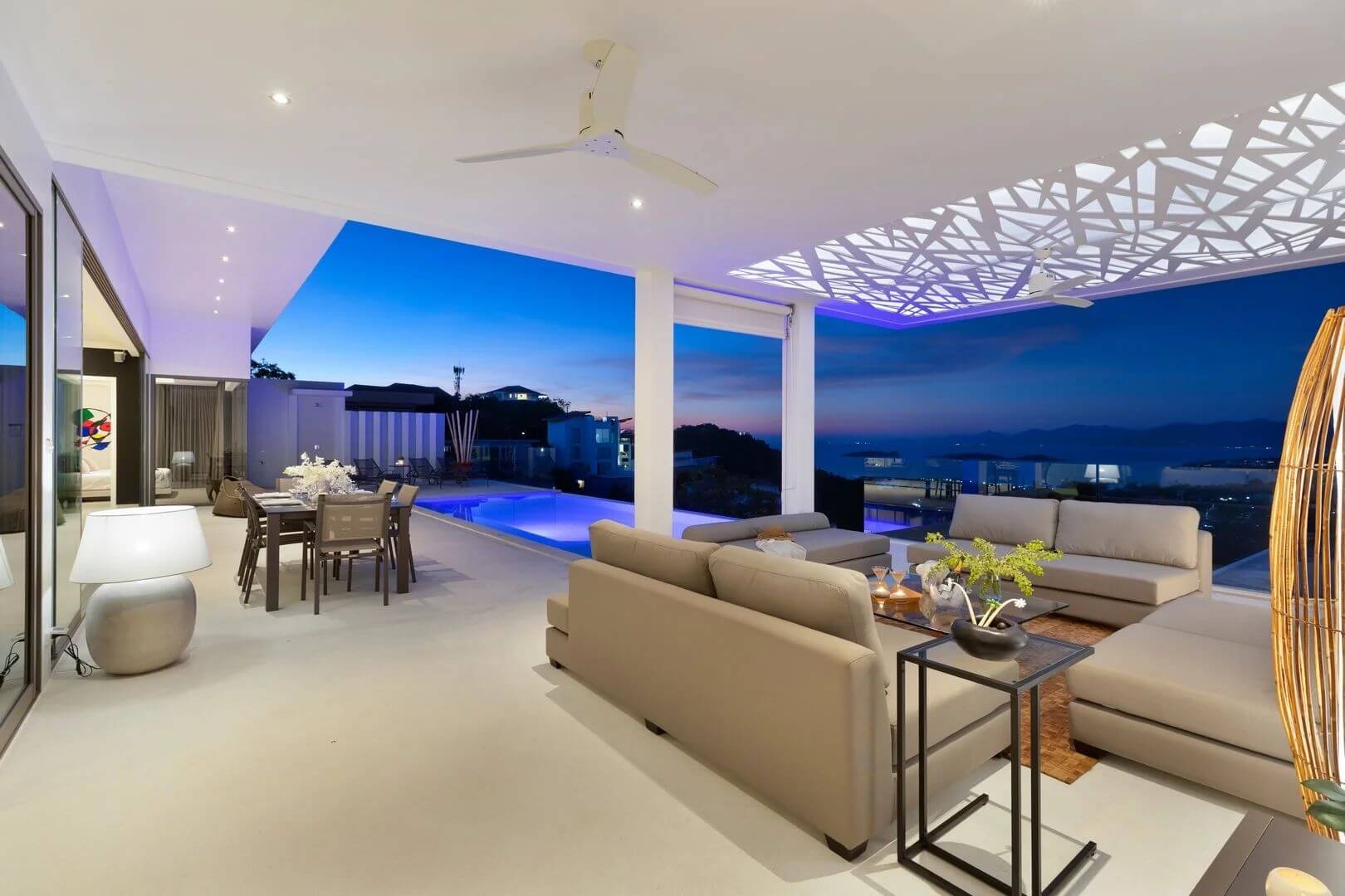 The sala after sunset, canopy lit, dining table glowing by the pool.