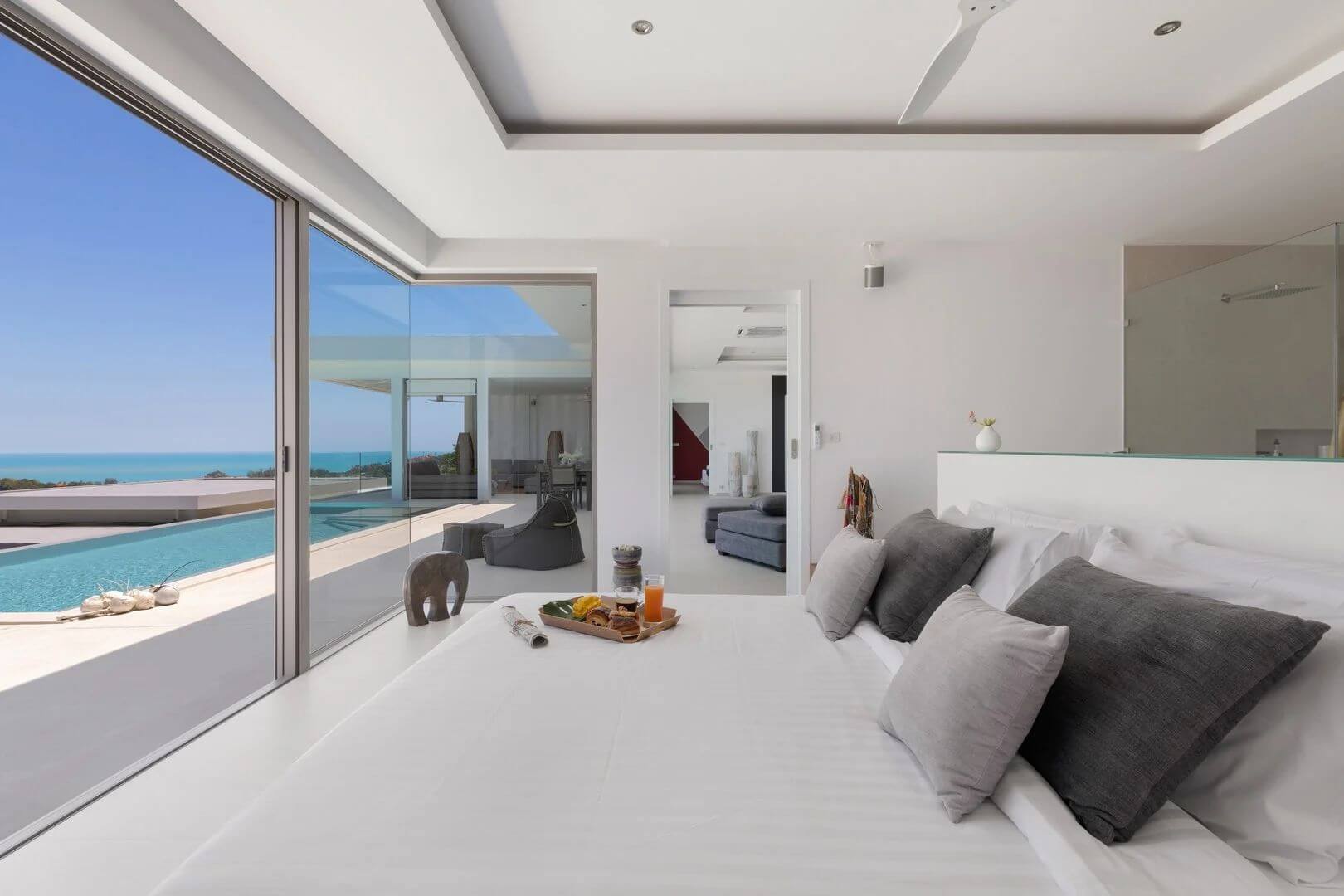 Suite one — white linens and a corner of glass over the pool and sea.