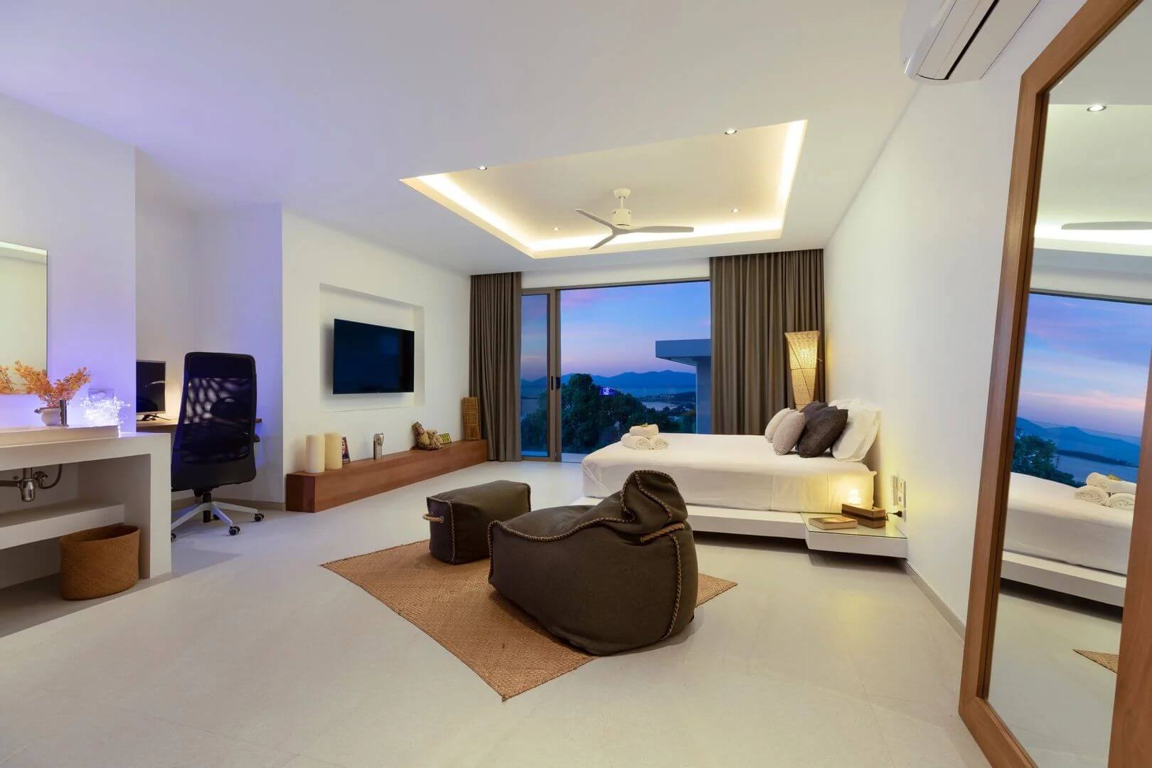 A suite dimmed to evening — cove lighting, desk, and the bay turning violet.