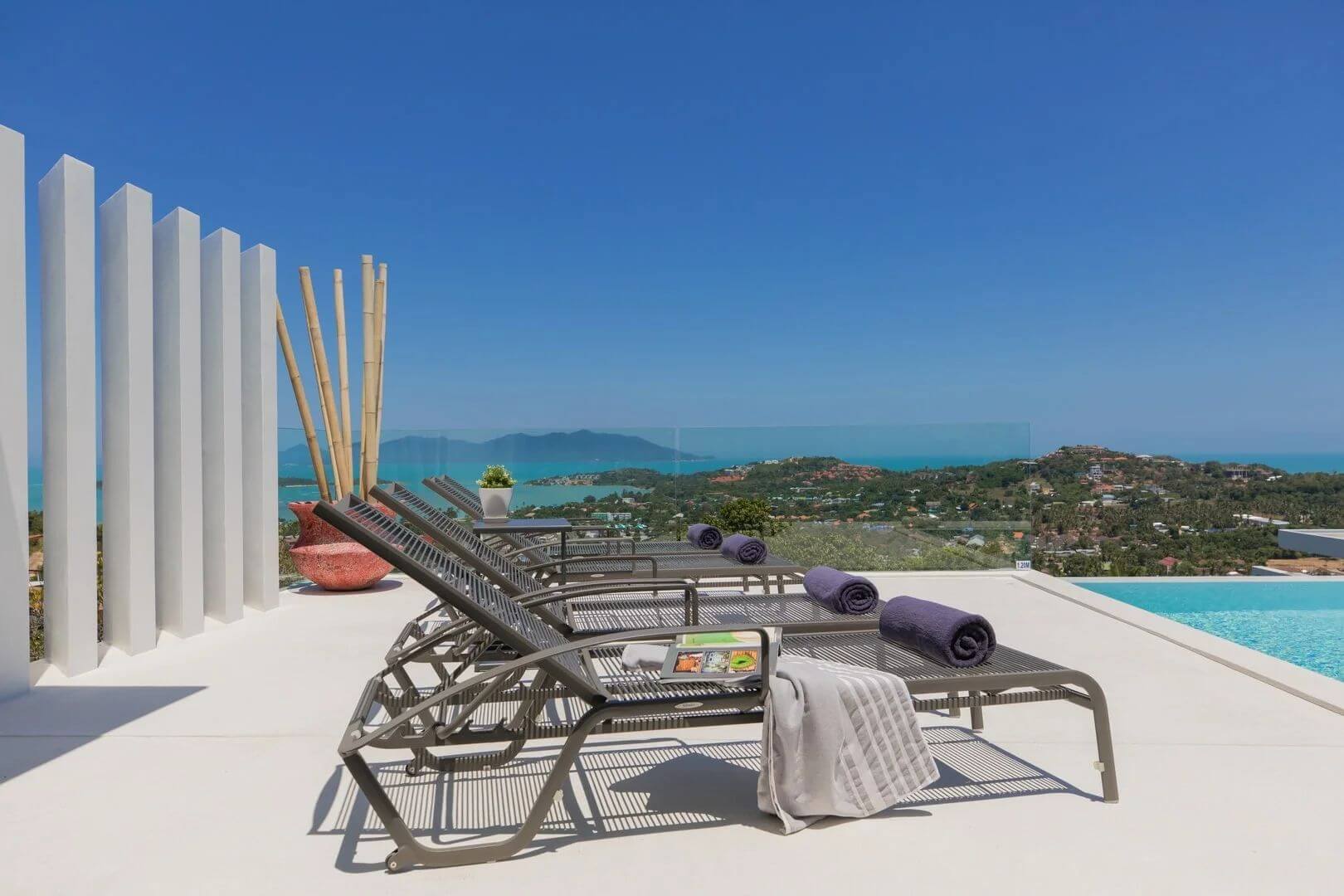 Sun loungers with rolled towels on the deck, white fins and bamboo behind.