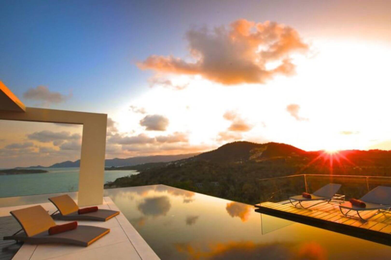 Sunset flaring over the infinity edge, loungers in silhouette.